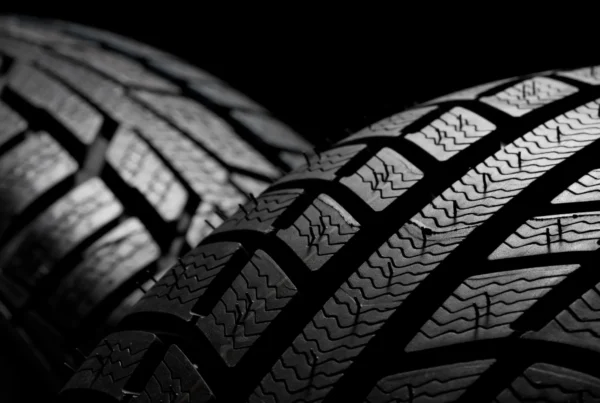 Extreme close-up of the grooved tread pattern on a new black tire against a dark background.